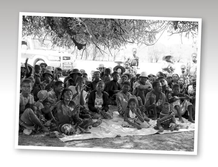Elderly person with solemn expression stands in a crowd of children.