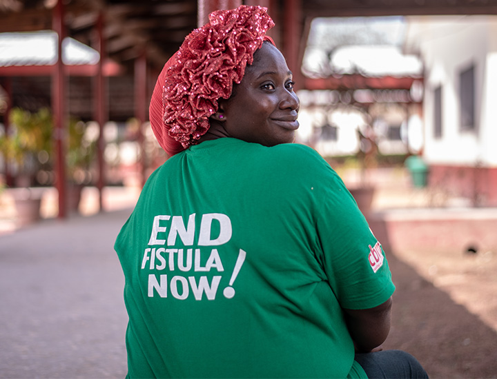 A woman in a green shirt that reads 'END FISTULA NOW!'