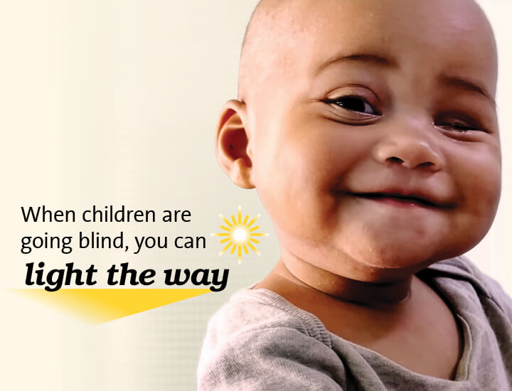 Text reads “When children are going blind, you can light the way,” accompanied by a stylized yellow sunburst graphic. On the right side, part of a child's head and ear is visible.